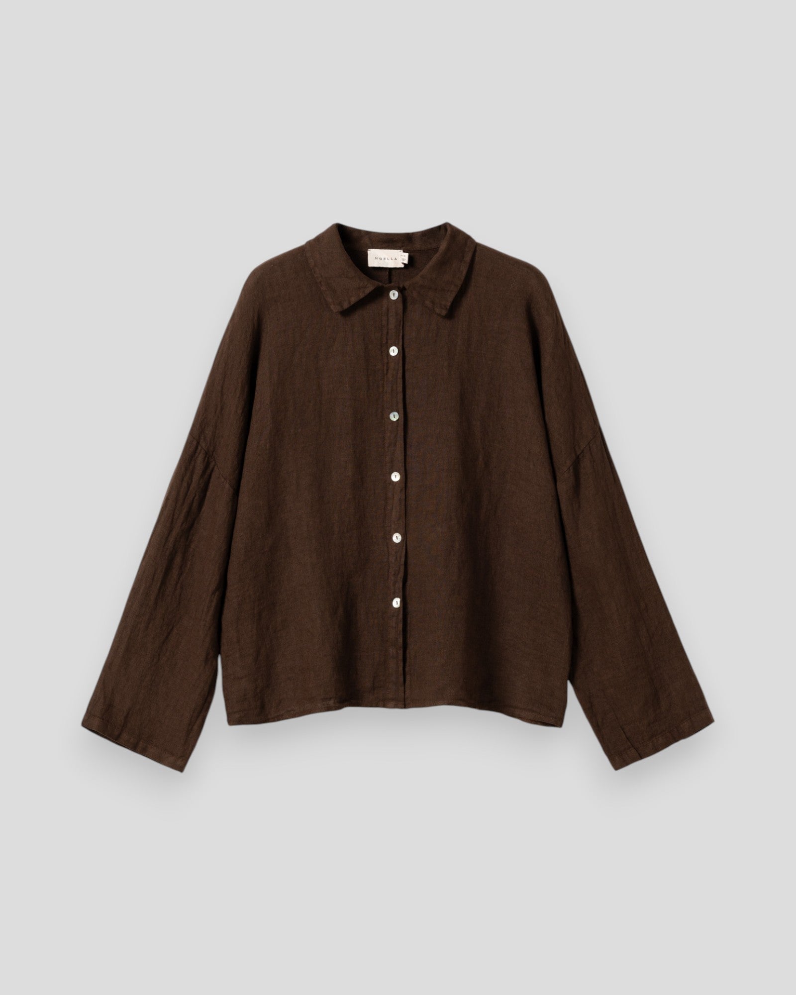 Kvinde i Noella Leanora skjorte i chokoladefarvet bomuld med knapper og langærmet design, afslappet og stilfuldt look.