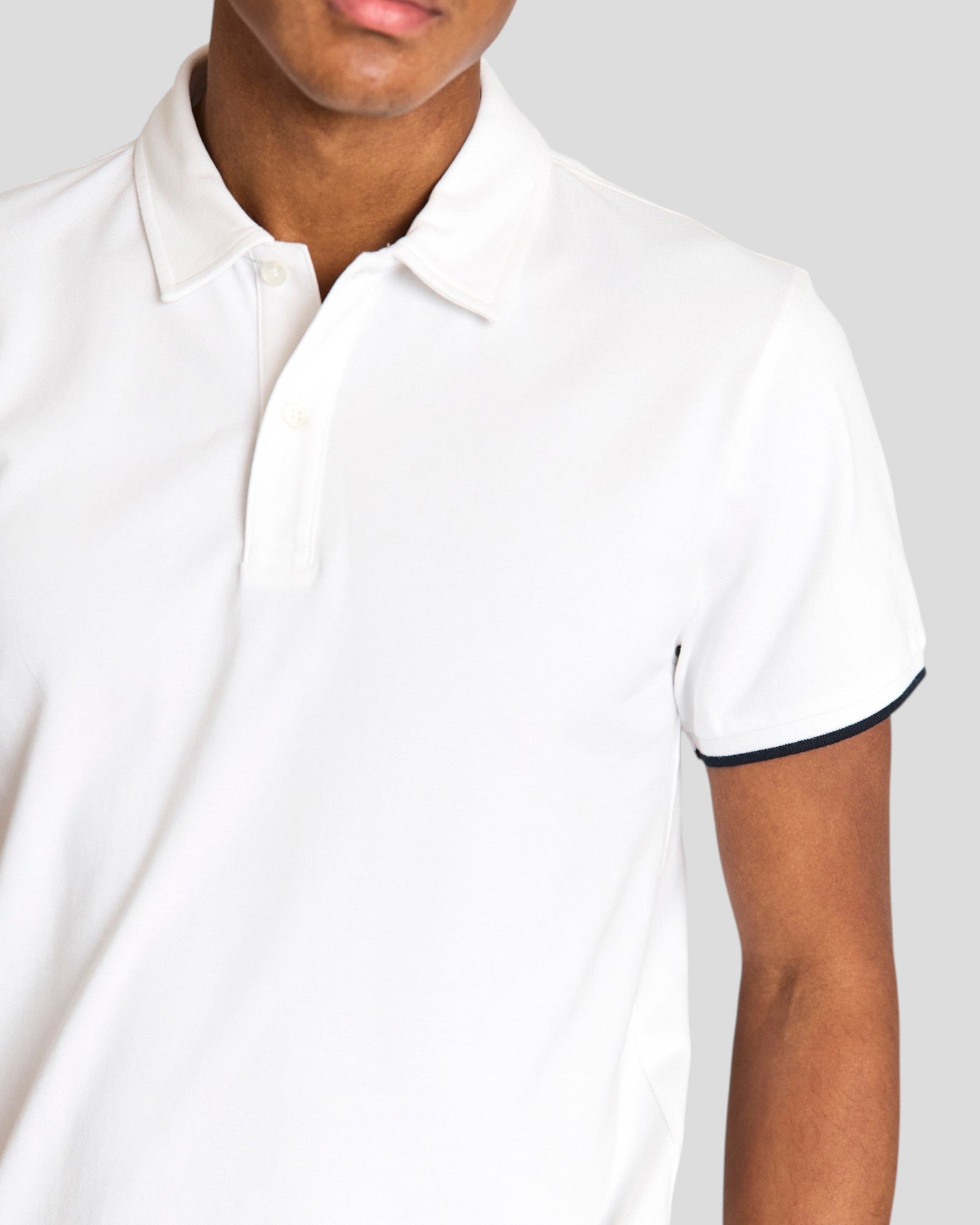 White Delos regular fit polo shirt by Bruun & Stengade, shown on a hanger with close-up of fabric and collar details.