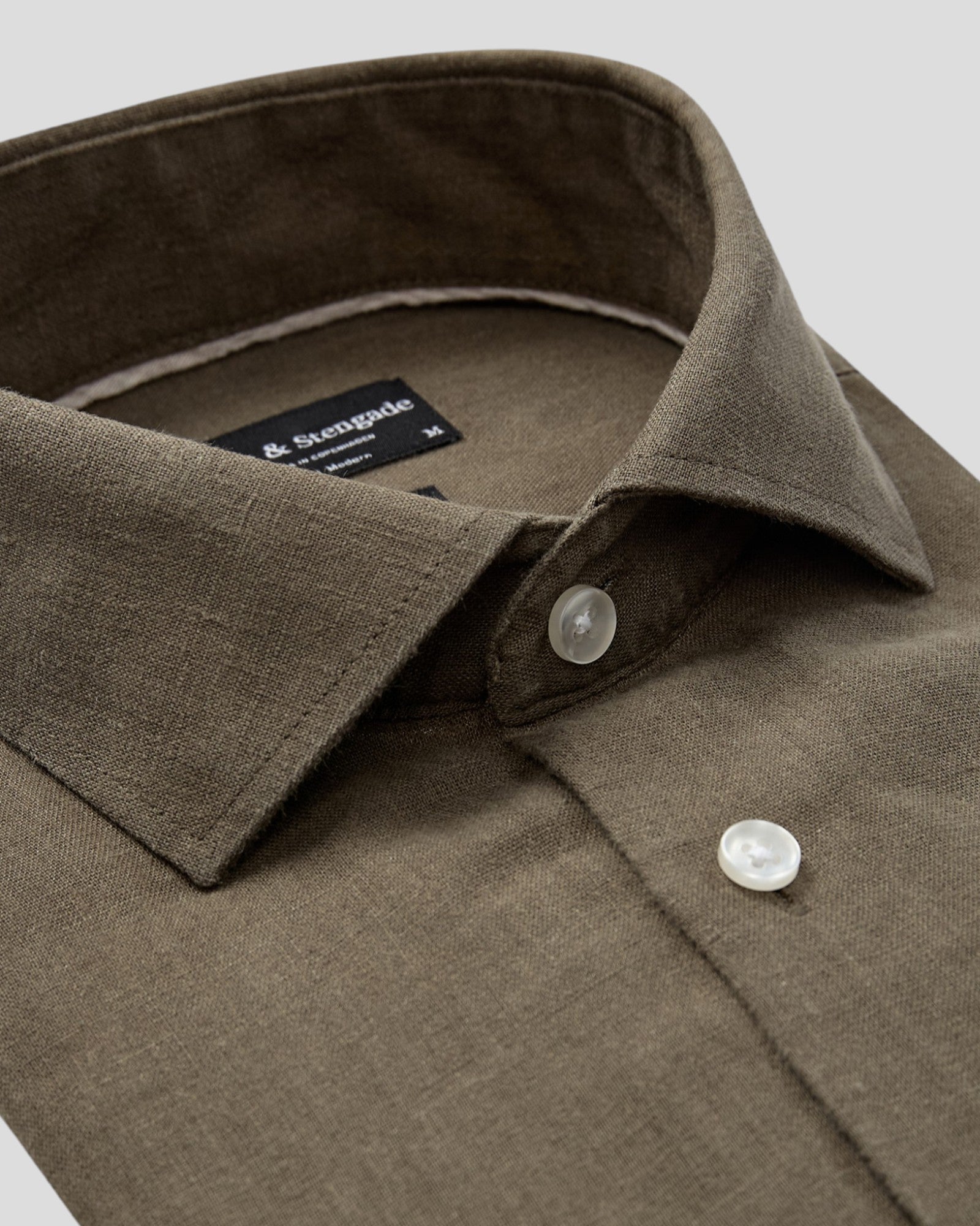 Green Tahaka Modern Fit Shirt by Bruun & Stengade displayed on a hanger, showcasing its sleek design and vibrant color.