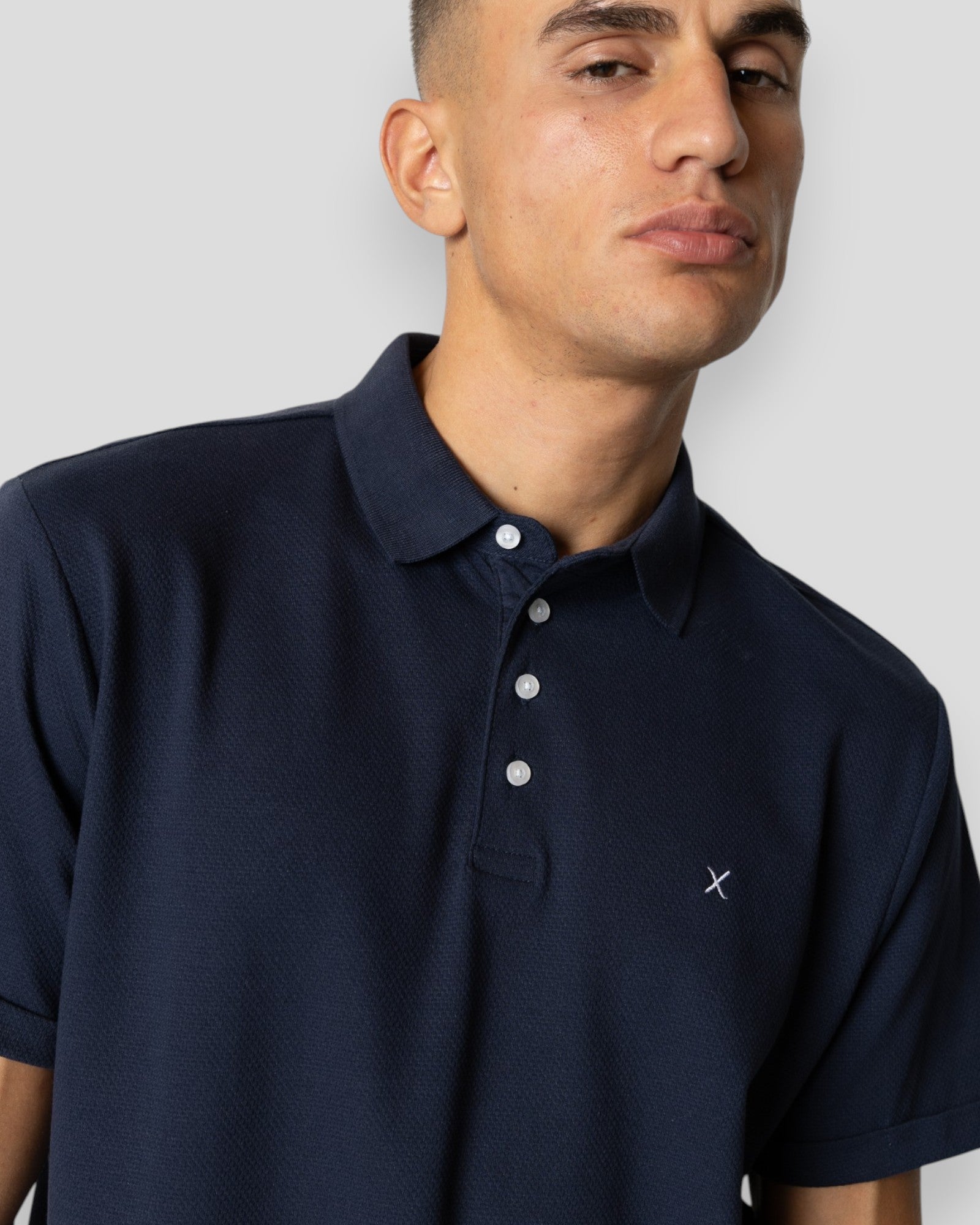Navy Silkeborg Stretch Polo by Clean Cut Copenhagen, shown on a hanger with a close-up of the fabric and collar details.