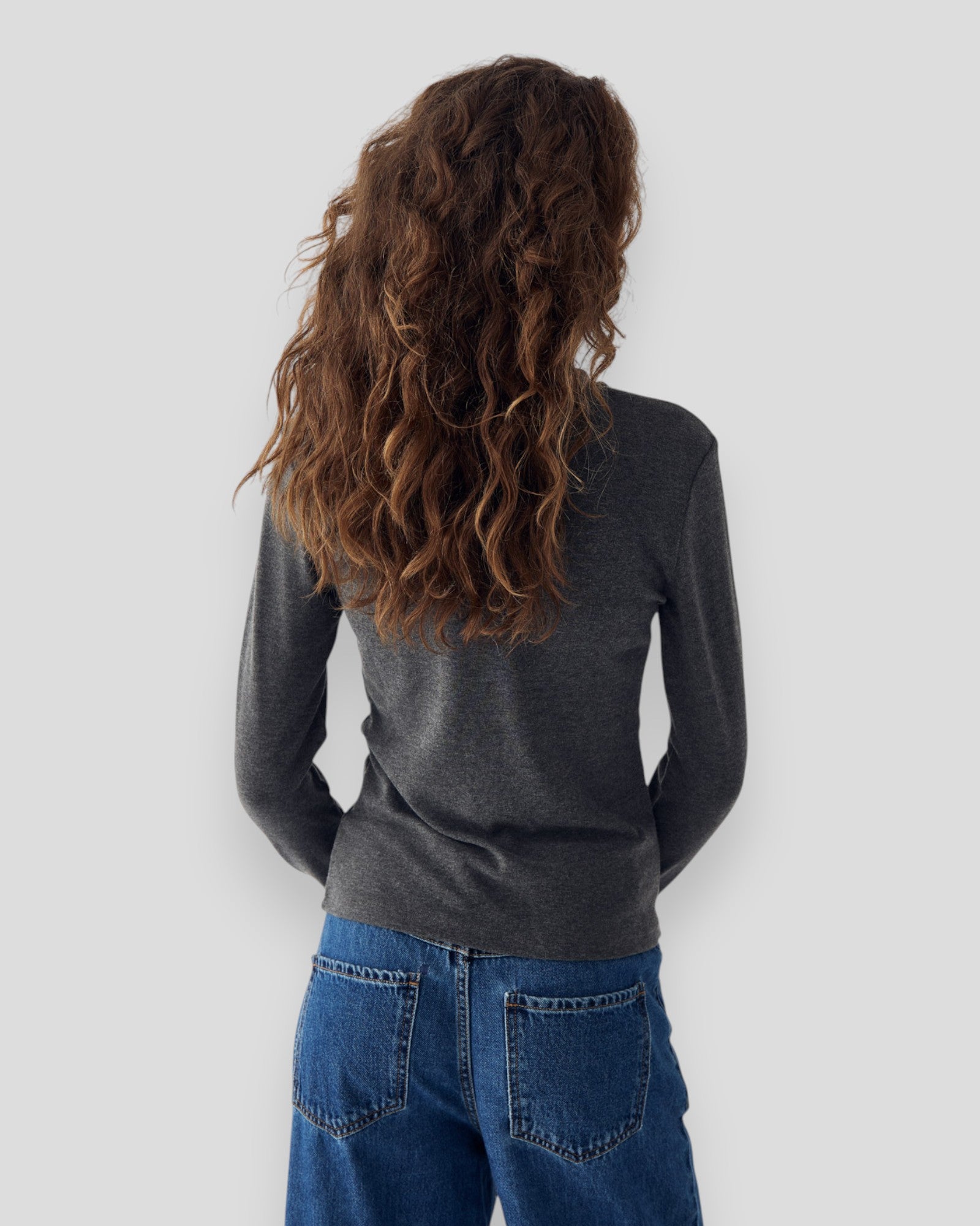 Dame i mørkegrå melange Noella Lidie LS Top, langærmet bluse i blødt stof, vist i et stilfuldt outfit.