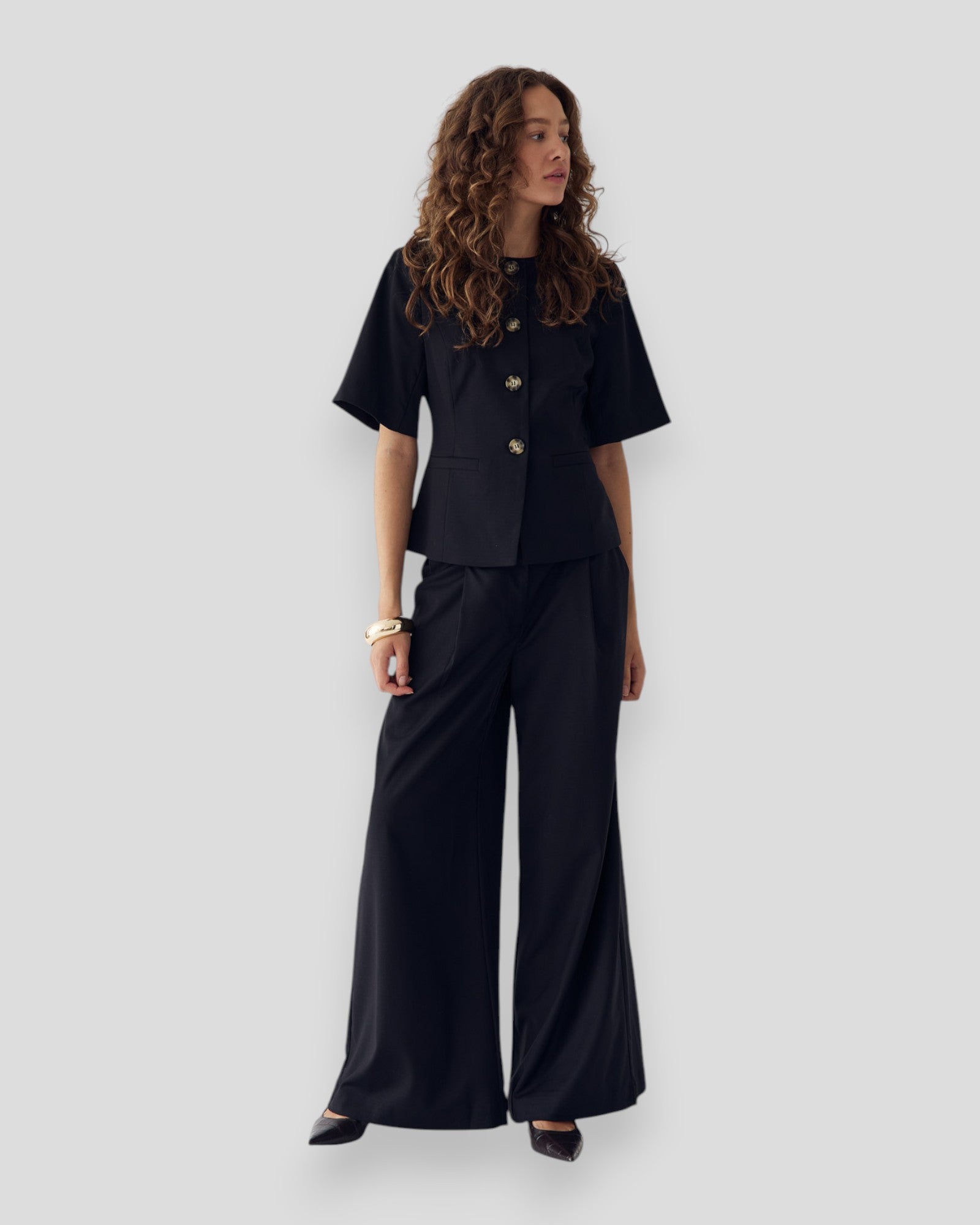 Black Kazia women's pants by Noella, featuring a sleek fit and modern style, shown on a model in a casual setting.