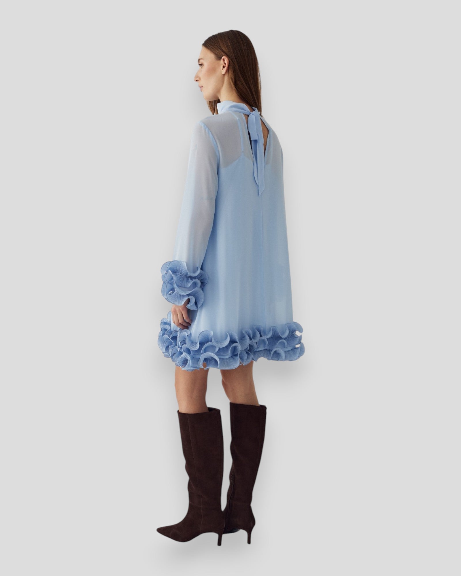 Lyseblå Noella Latania kjole med blødt stof og elegant snit, vist på modellen foran en neutral baggrund.