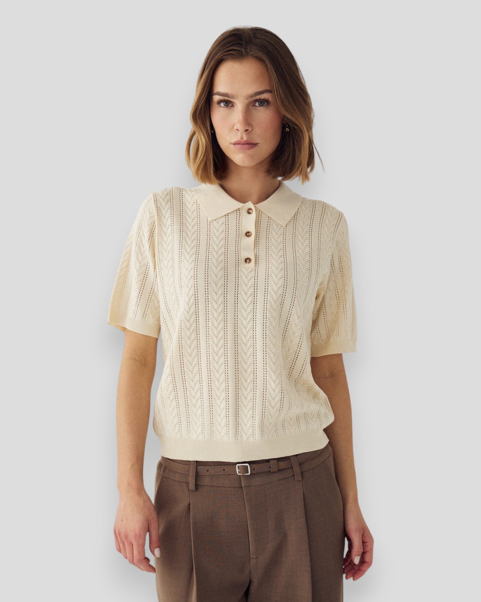 Kvinde i ivory N-Mecca strikket polo fra Noella, vises i dette billede med krave og korte ærmer.