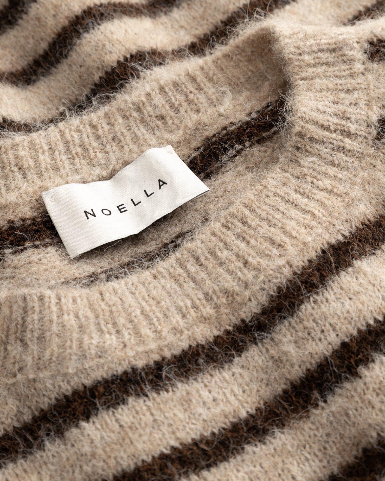Damestrik fra Noella, N-Mafalda Knit i brun sandstribet, blødt og behageligt, vist på model.