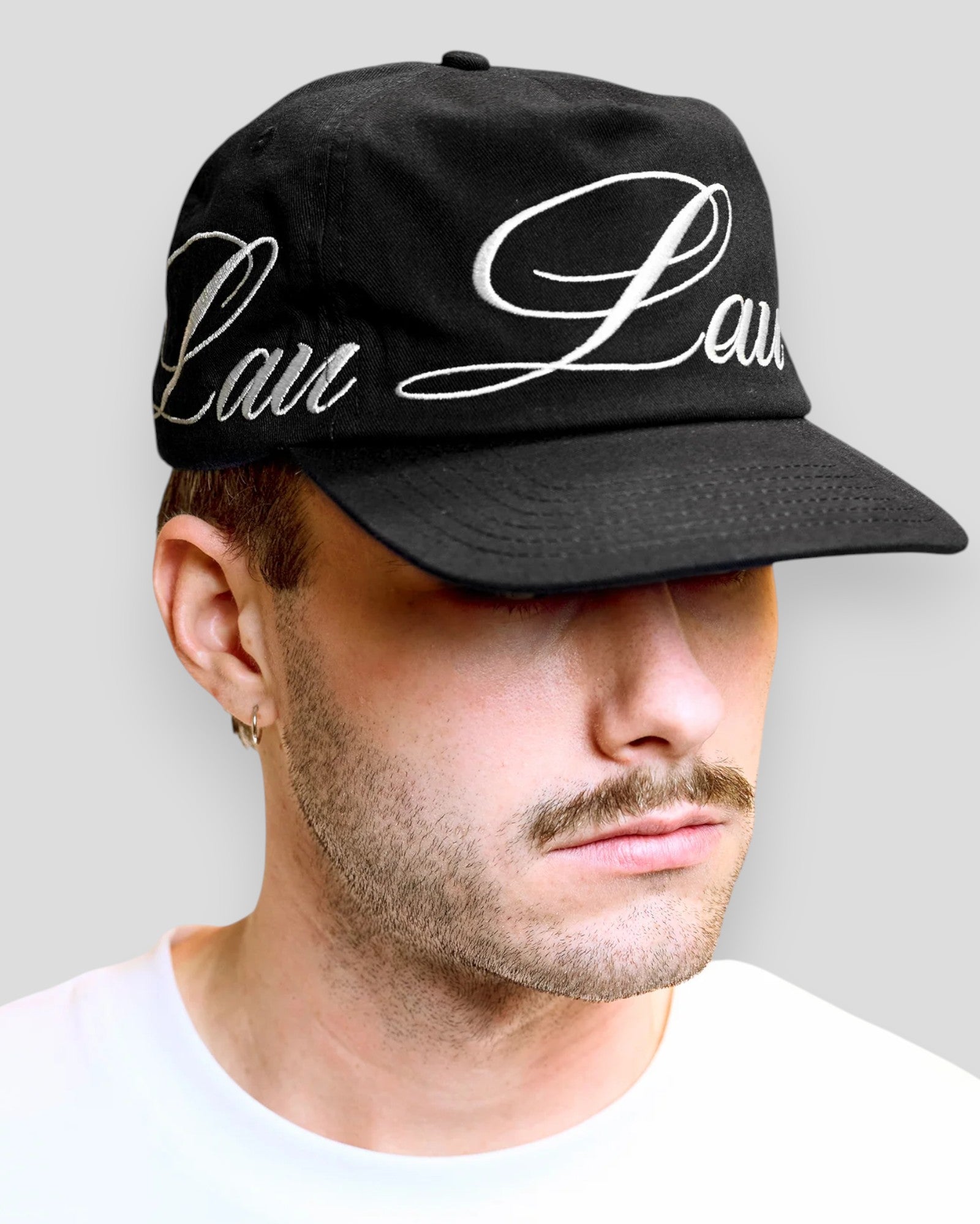 Sort baseball cap fra Lau Lau med rund, sort løkke foran, vist på en model.