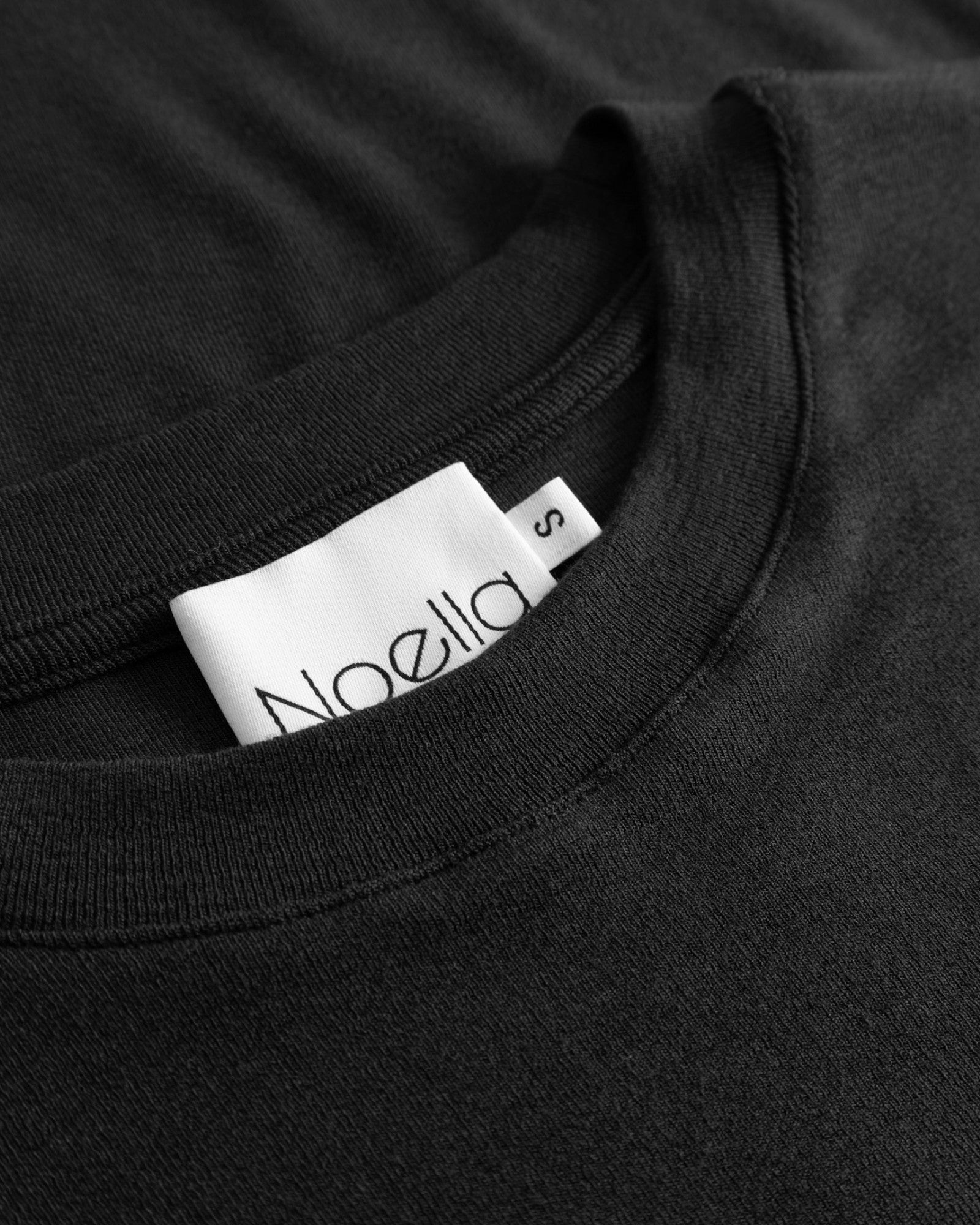 Sort Noella Lidie LS Top i blødt stof med rund hals og lange ærmer, vist på model.