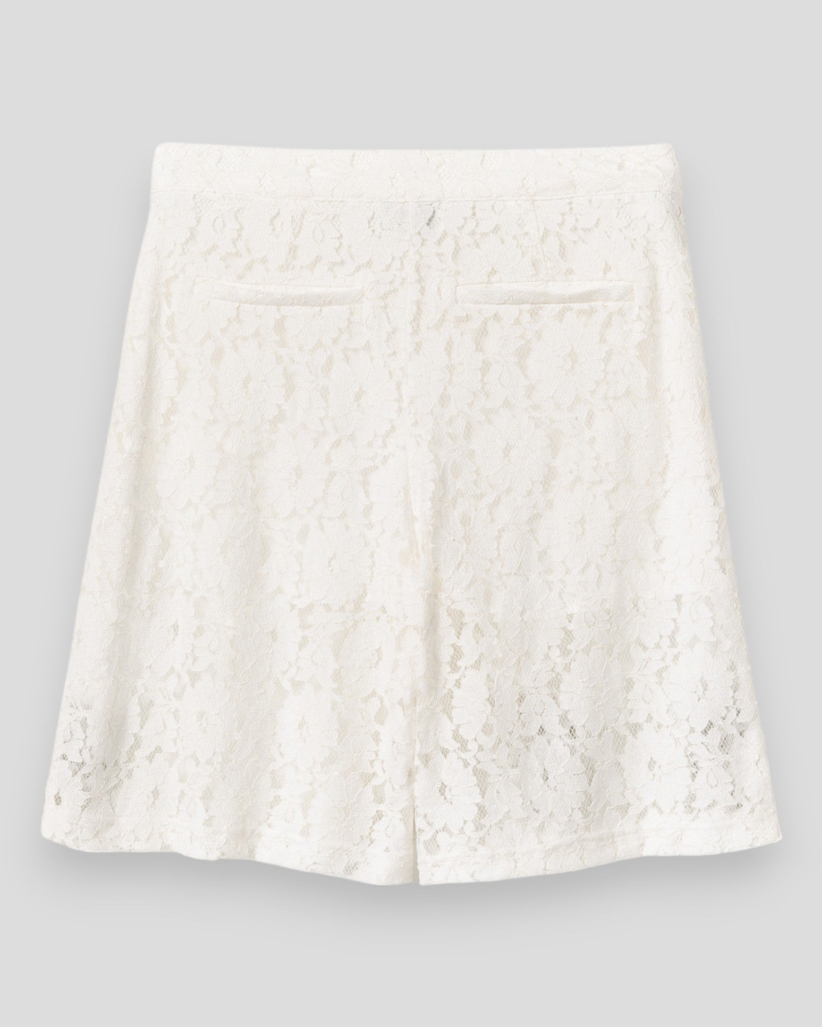 Kvinde i hvide Noella N-Kaziana MW shorts, afslappet stil, sidder på en stol i lyst, komfortabelt sommeroutfit.