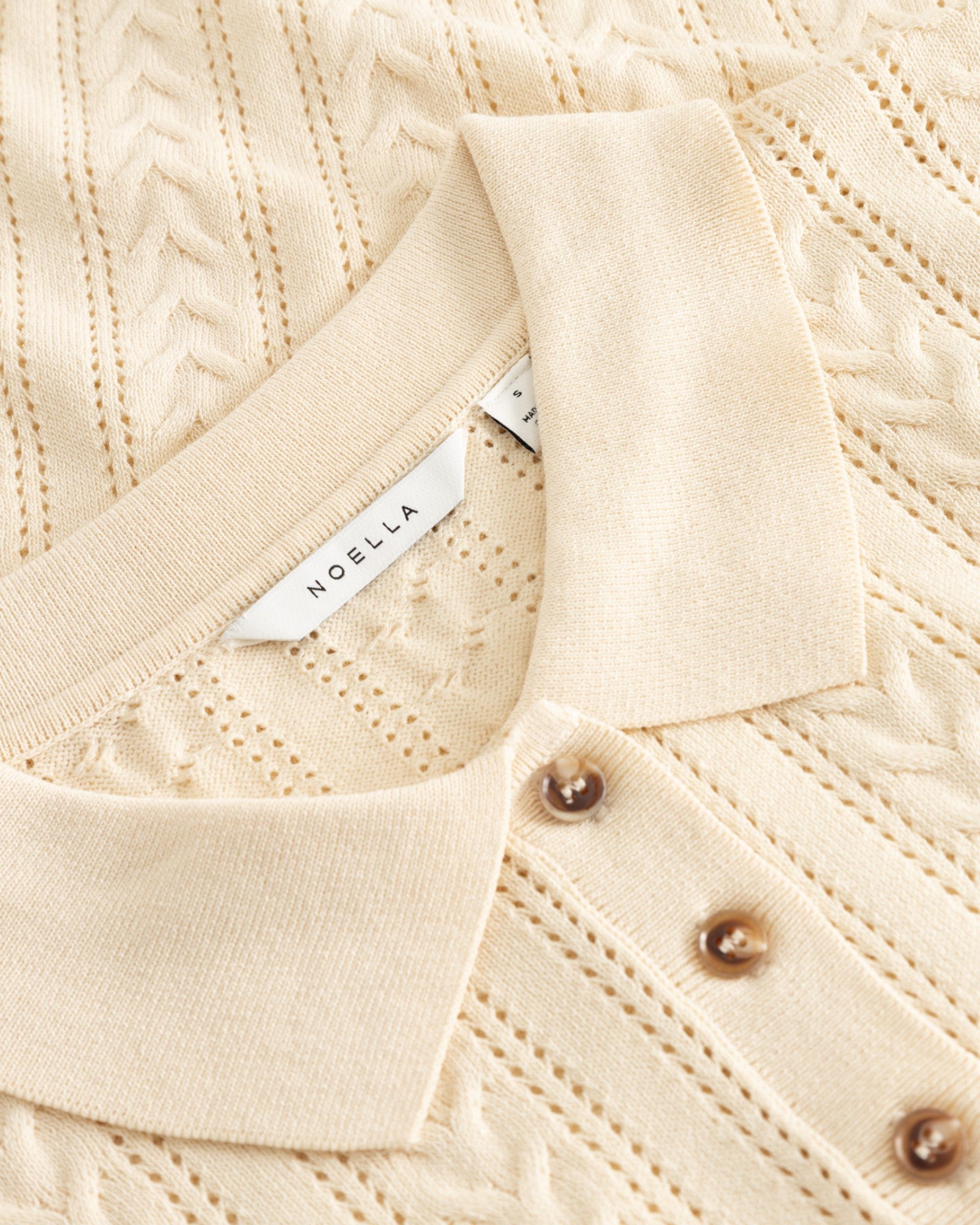Dame-polo i N-Mecca Knit Polo i ivory fra Noella, vises med rund hals og strikket tekstur.