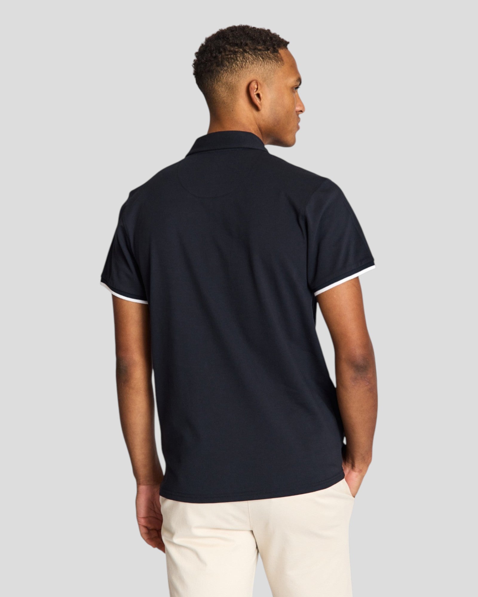 Navy Bruun & Stengade Delos regular fit polo shirt displayed on a hanger with a close-up of the fabric and collar detail.