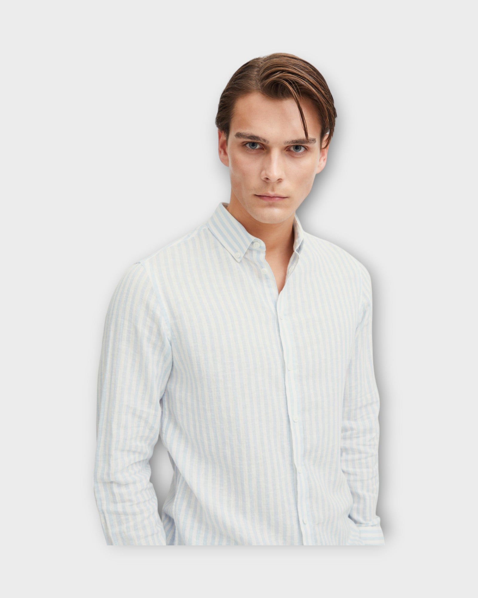 Anton Striped Linen Shirt Chambray Blue fra Casual Friday. Blå og hvid stribet hørskjorte med langt ærme til mænd. Her set i closeup på model.
