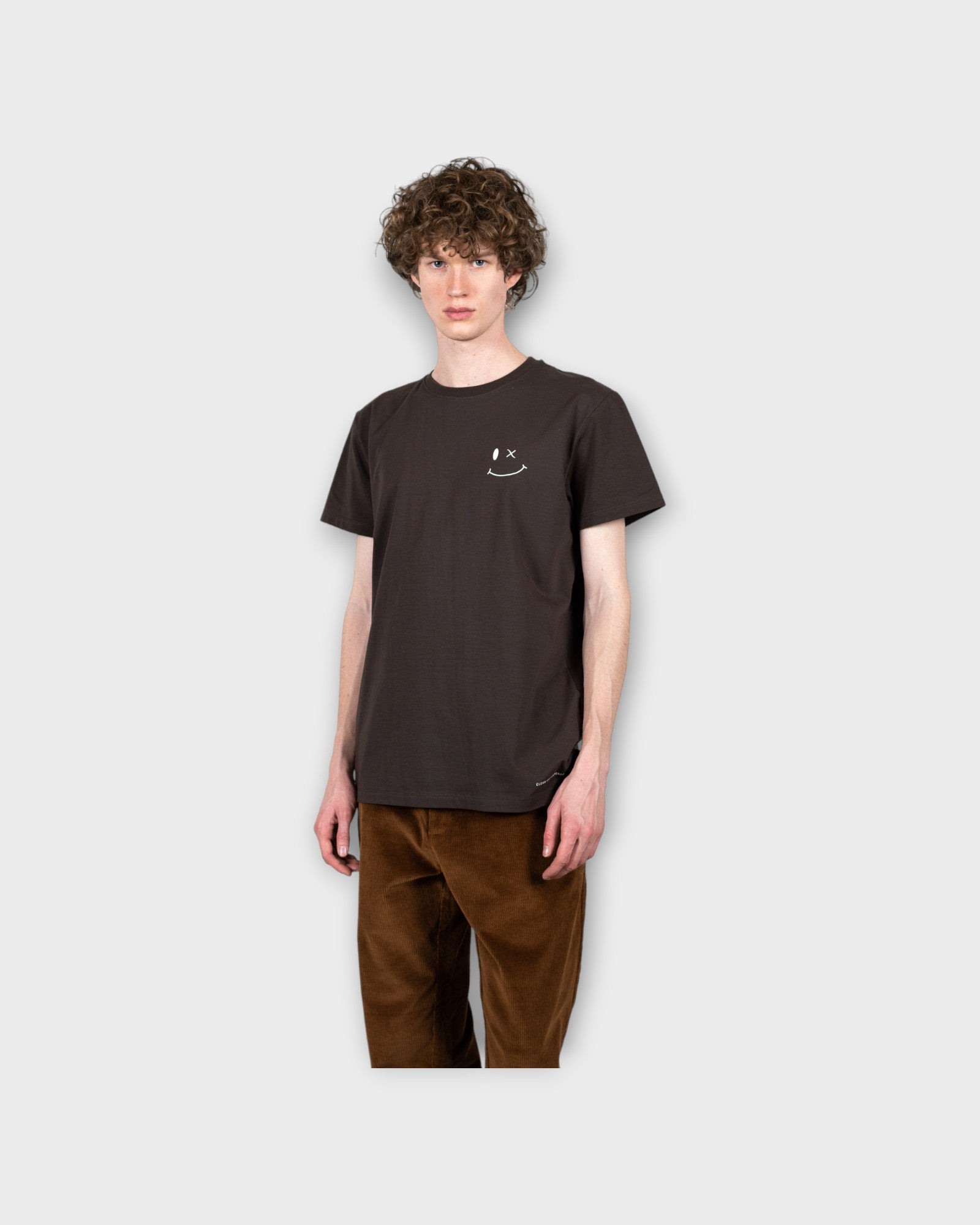 Patrick Organic Tee Dark Brown. Brun Clean Cut Herre T-shirt med smiley logo. Her set i closeup på model.