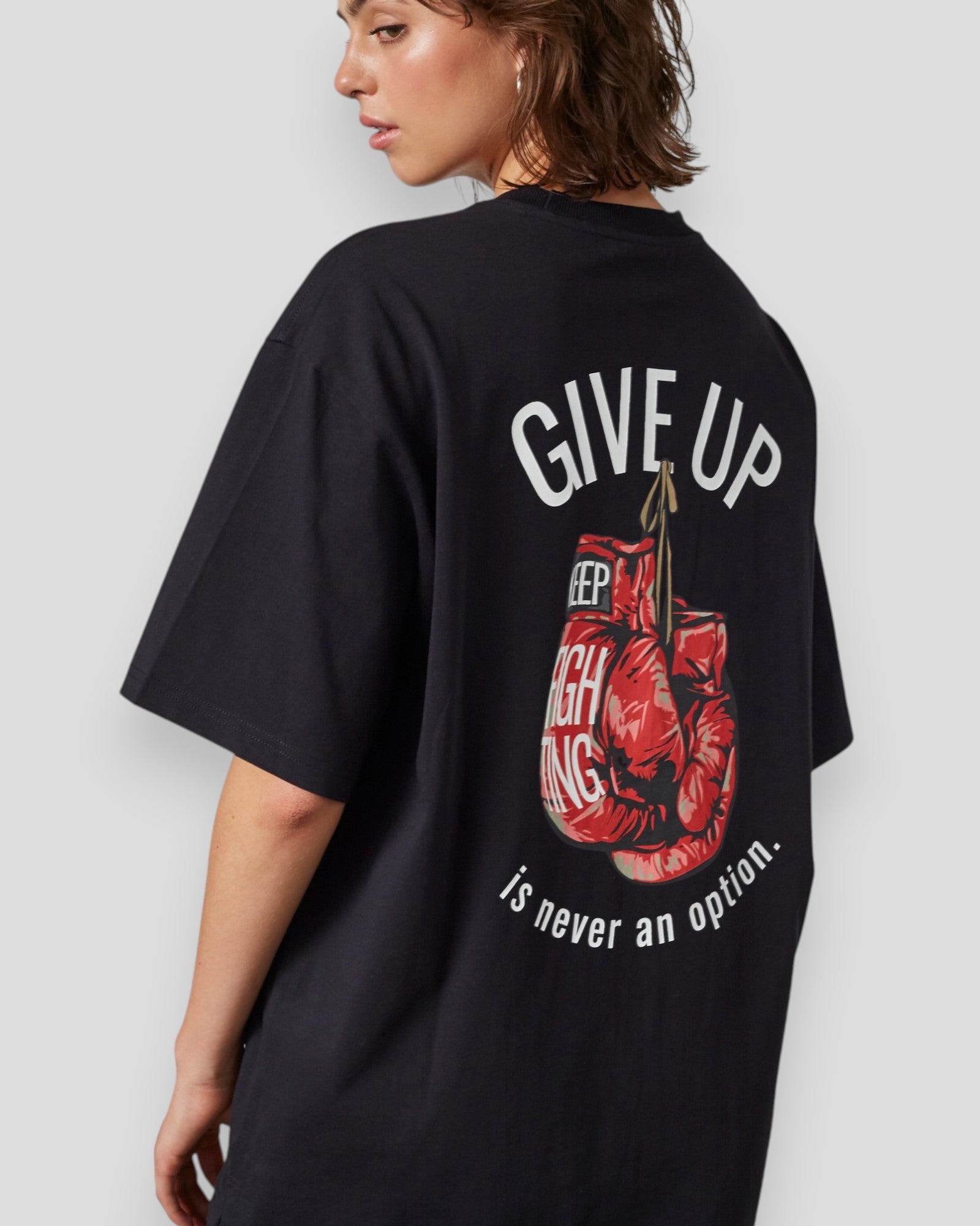 Sort Everlast Never Give Up T-shirt med sort design og tekst, vises på modellen foran hvid baggrund.