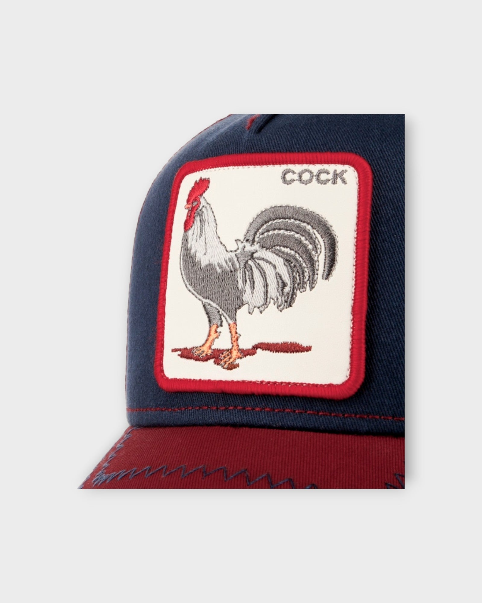 The Cock Navy - Mørkeblå Goorin Bros Trucker Cap til Mænd. Her ses et closeup af badge.