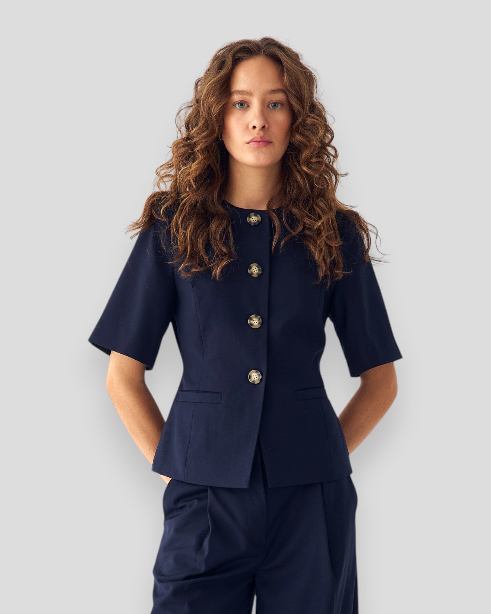 Navy women's blazer by Noella, tailored fit with lapels, worn open over a blouse, displayed on a hanger.