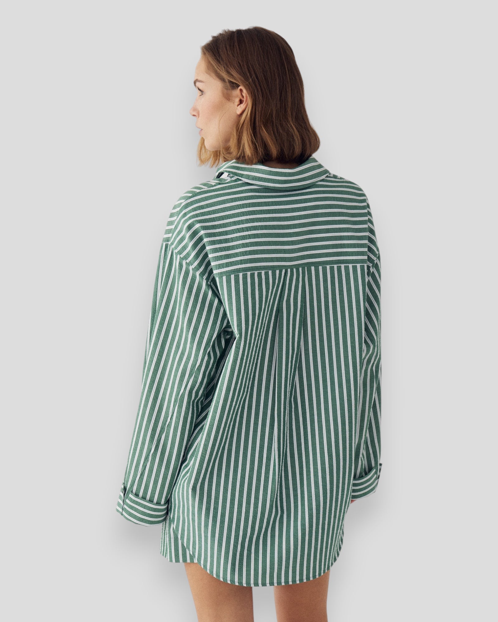 Kvinde i Noella N-Marlon skjorte i grønstribet design med lange ærmer og knappestolpe, afslappet og stilfuldt look.