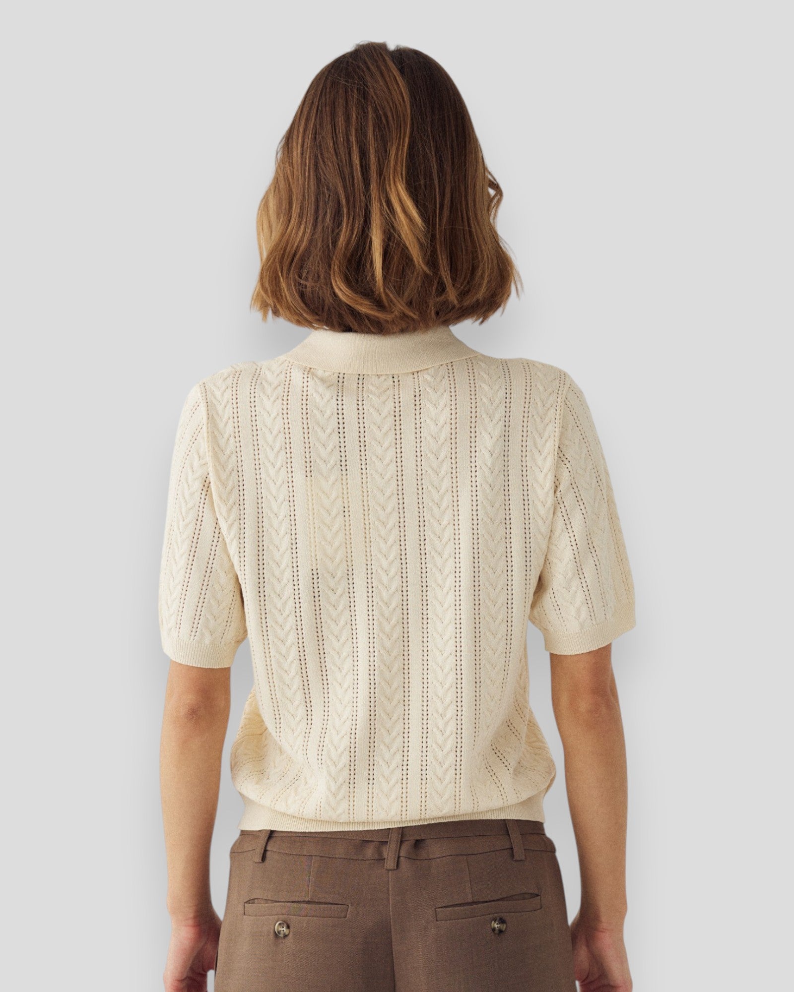 Kvinde i ivory N-Mecca strikket polo fra Noella, vises i et afslappet look, med detaljeret tekstur og klassisk design