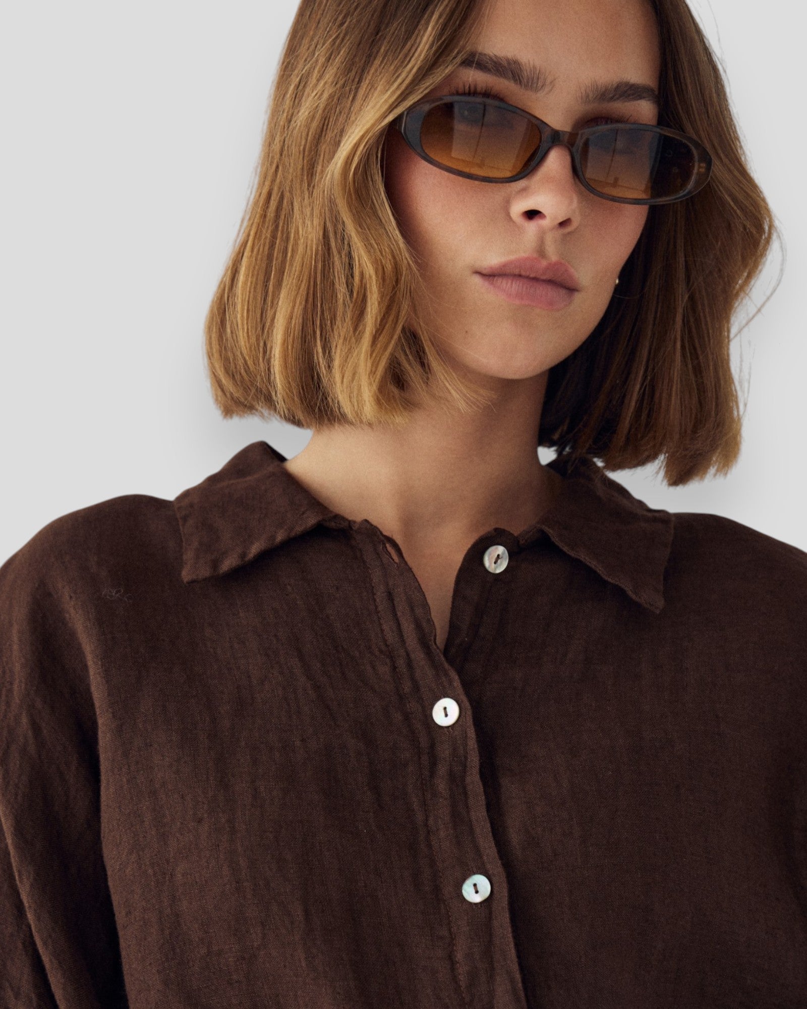 Chokoladefarvet Noella Leanora kvinderbluse med lange ærmer og løs pasform, vist på en model.