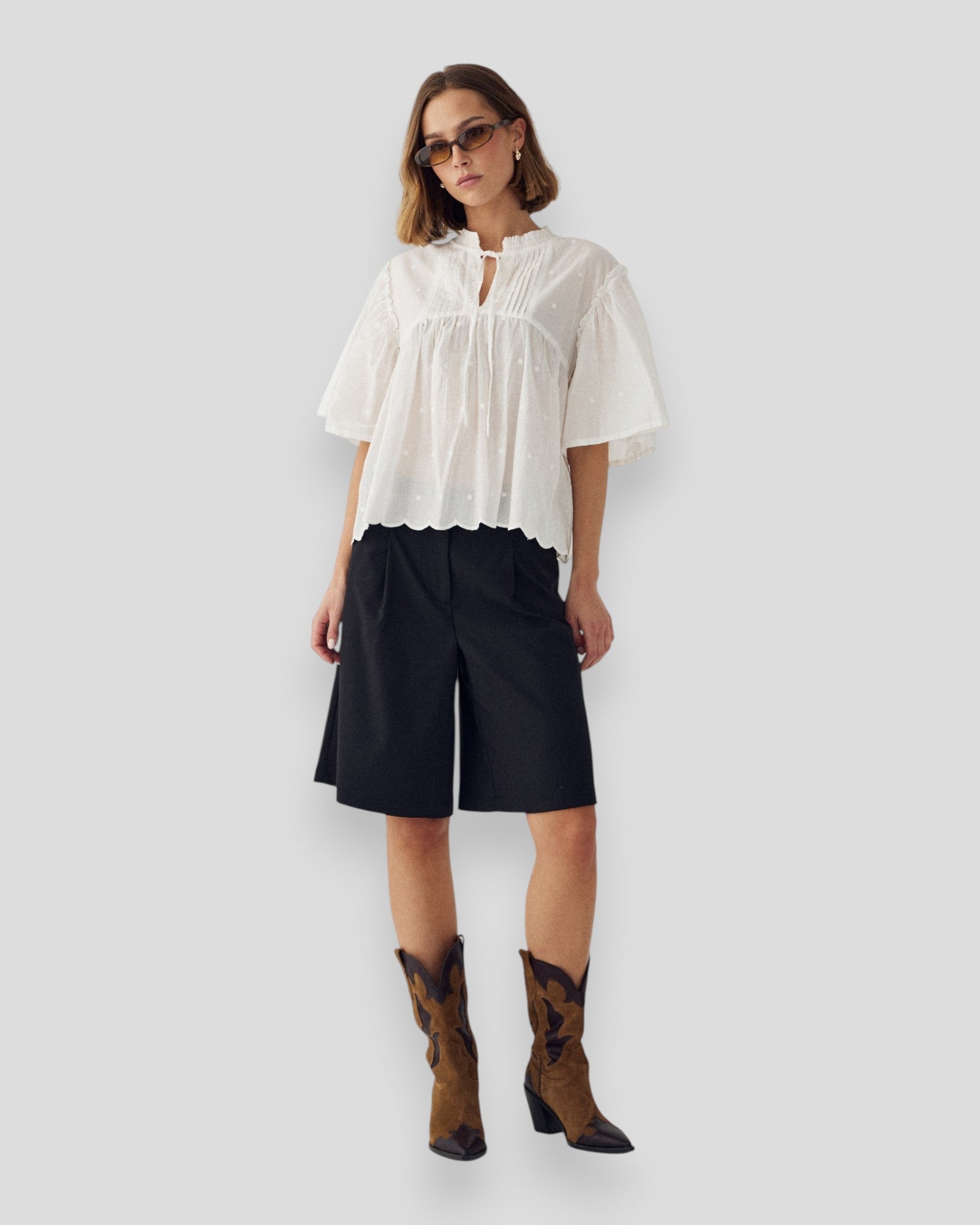 Hvid N-Marielle damebluse fra Noella med langærmet design, vises på model med let bukser, afslappet og stilfuld.