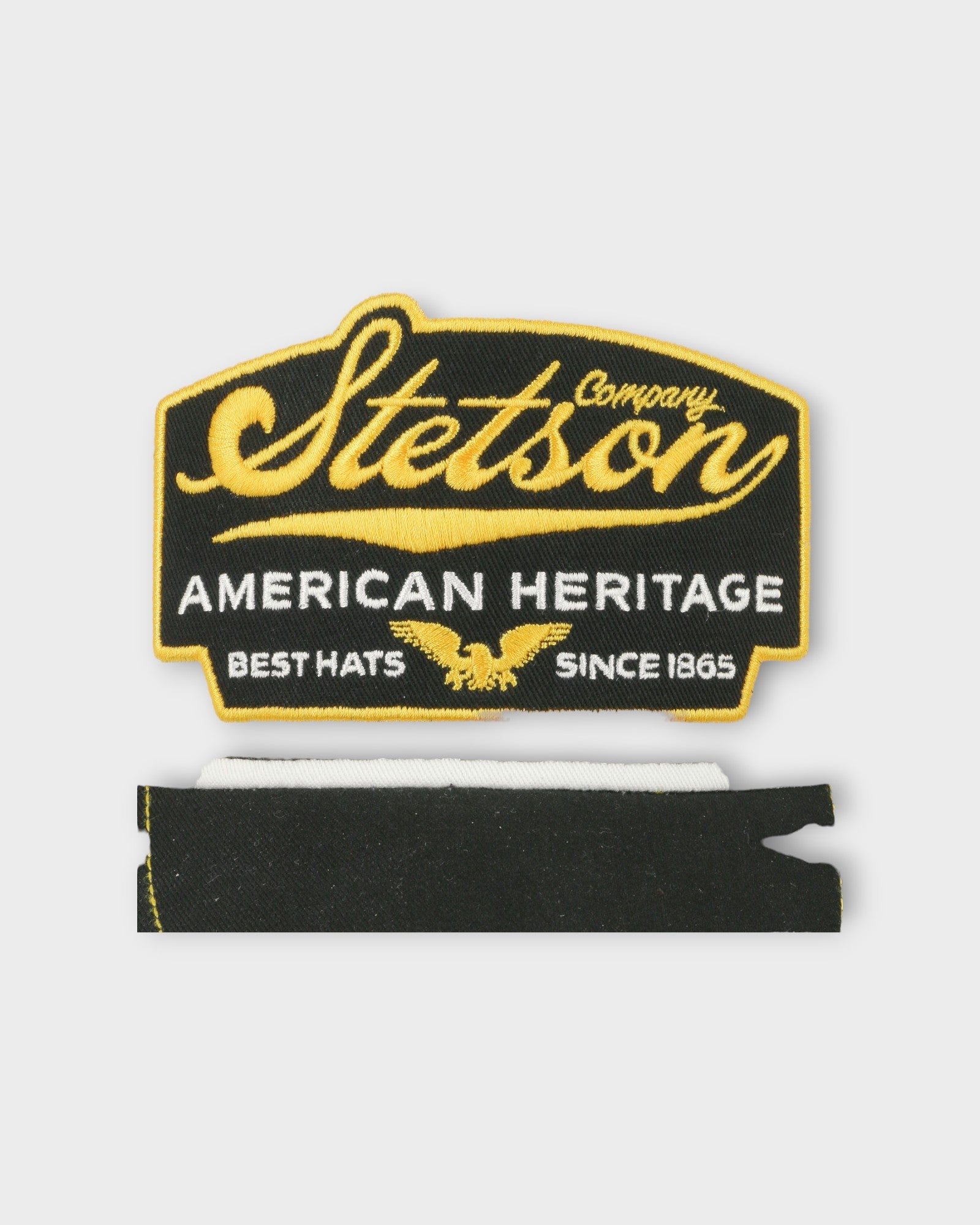 Trucker Cap American Heritage Black fra Stetson Hats. Sort kastet til med med hvid og gul. Her set broderingen i closeup.