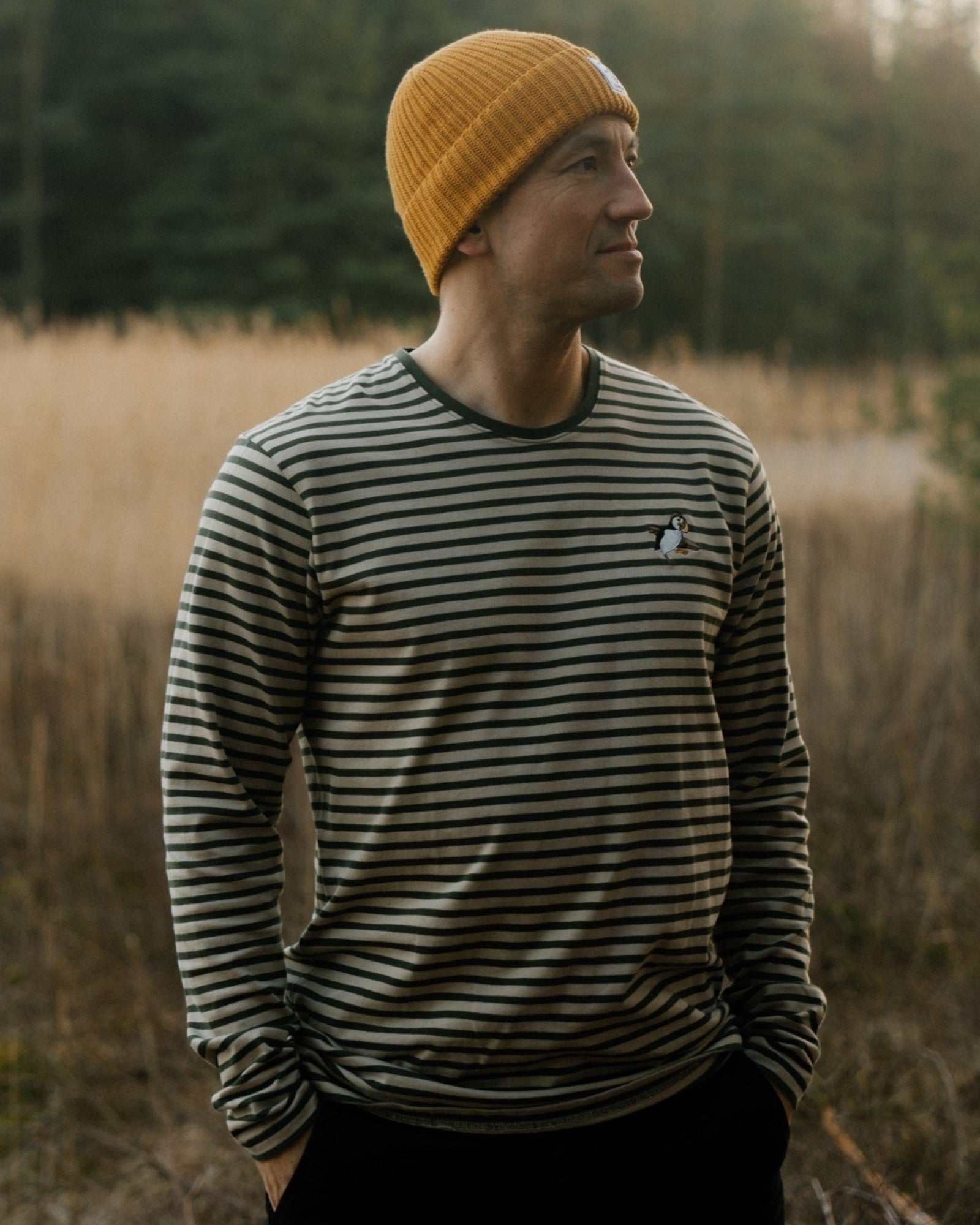 The Sons online Ahoy! Mini Sea Parrot long sleeve striped shirt in riffle green and white pepper on a man with a beanie